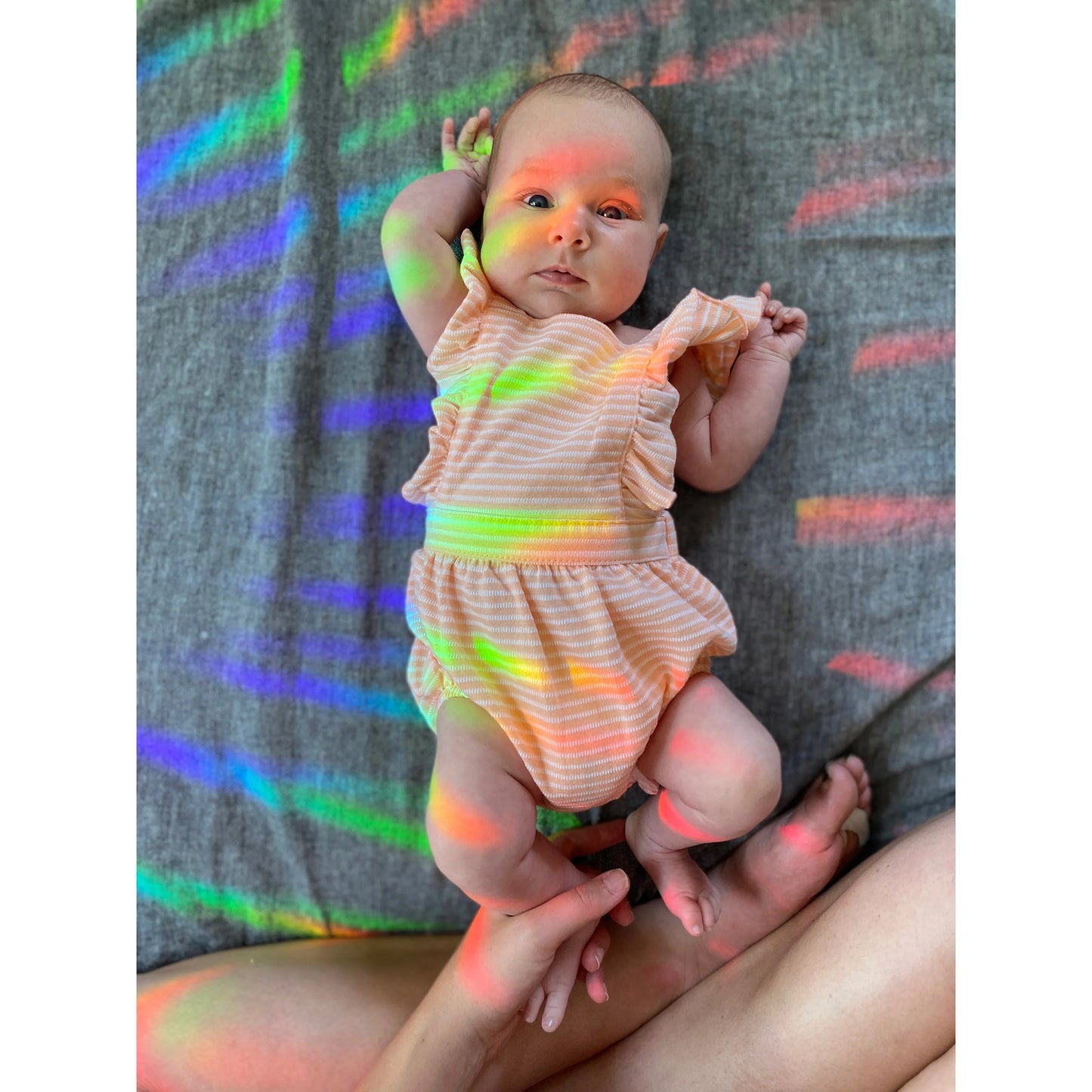 Colorful rainbows from suncatcher sticker shining over cute baby