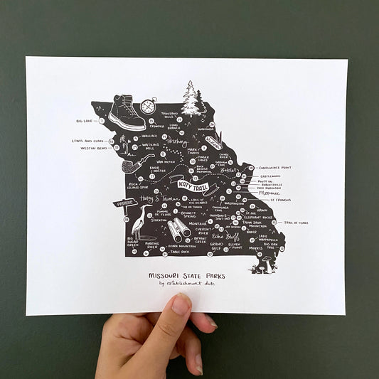Hand holding black and white illustrated map art print of Missouri State Parks